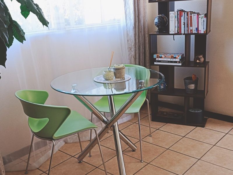 A compact dining area featuring ceramic tile flooring and natural light from a nearby window.