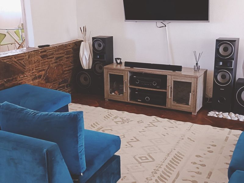A cozy living room featuring a distinctive stone accent wall and classic parquet flooring, creating a warm and inviting atmosphere.