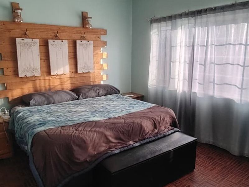 A bedroom featuring parquet flooring and large windows with curtain rails, providing natural light.