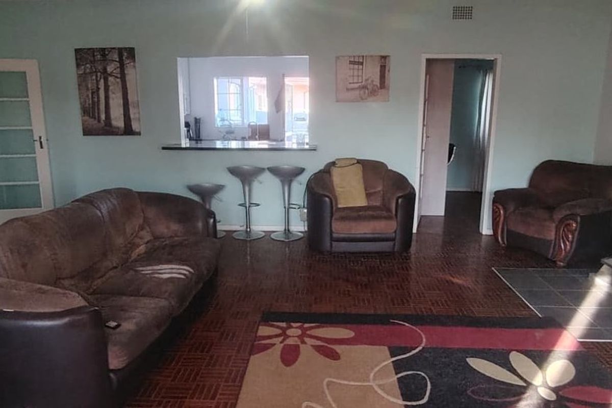 Spacious living room featuring traditional parquet flooring, a built-in fireplace, and a convenient pass-through window connecting to the kitchen area.