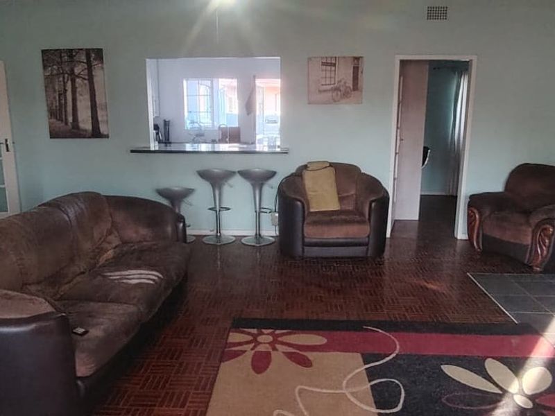 Spacious living room featuring traditional parquet flooring, a built-in fireplace, and a convenient pass-through window connecting to the kitchen area.