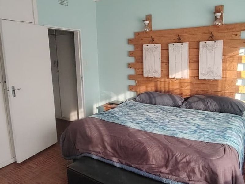 A bedroom featuring built-in cupboards, parquet flooring, and a ceiling vent, offering a functional space with potential for modern updates.