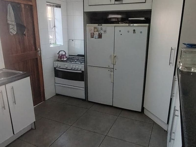 A functional kitchen featuring built-in cabinetry, a gas stove, double sink, and tiled flooring, offering a practical layout for daily meal preparation.
