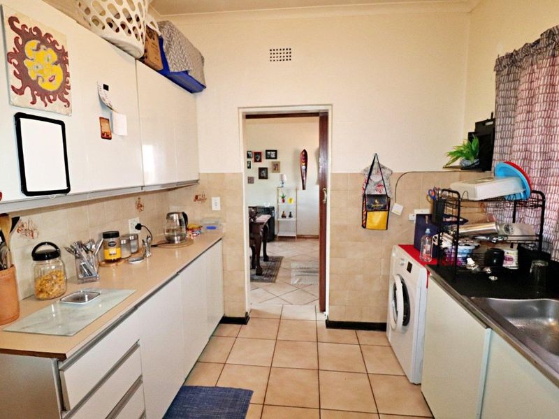 A functional kitchen featuring built-in cabinetry, laminate countertops, a stainless steel sink, and tiled finishes, providing a practical workspace for daily culinary needs.