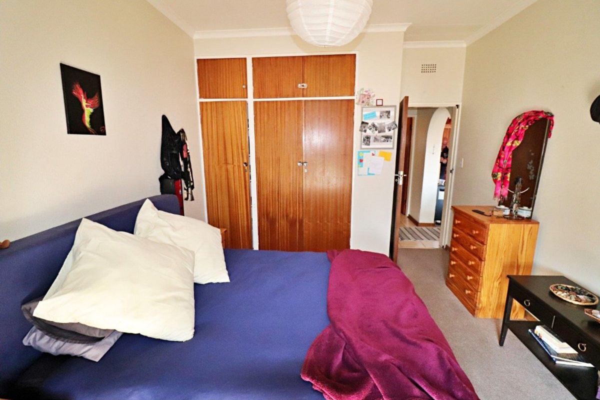 A bedroom featuring built-in wooden cupboards, carpeted flooring, and a coved ceiling, offering a functional space with potential for modernization.