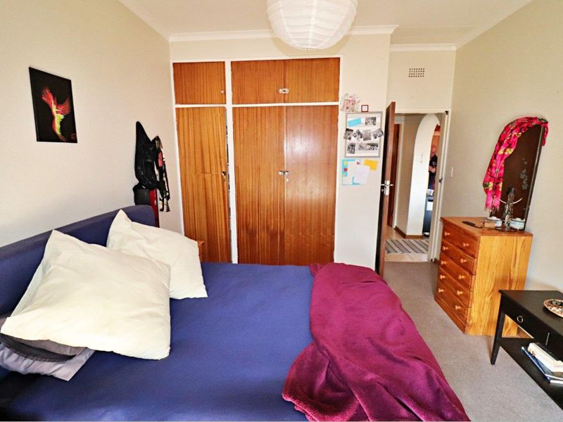 A bedroom featuring built-in wooden cupboards, carpeted flooring, and a coved ceiling, offering a functional space with potential for modernization.