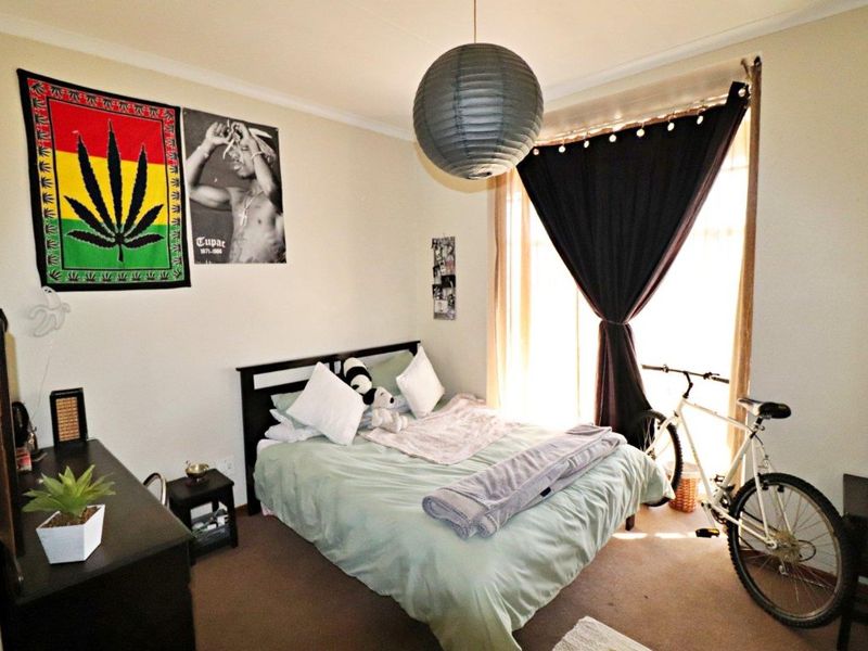 A standard bedroom featuring carpeted flooring and a window with curtain fixtures, providing a functional living space.