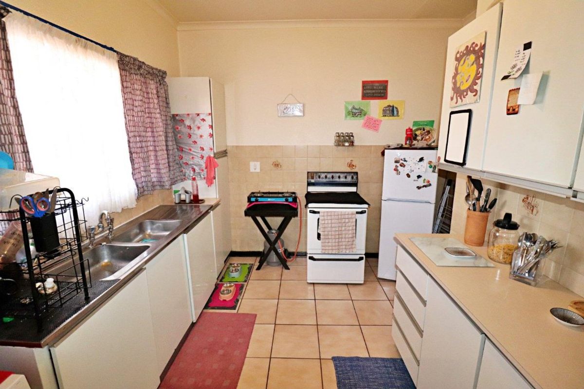 A functional kitchen featuring double stainless steel sinks, tiled splashbacks, ceramic flooring, and built-in cabinetry with laminate countertops.