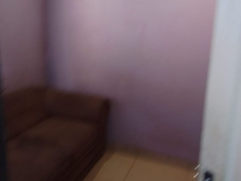 A small bedroom space featuring plain wall finishes and tiled flooring.