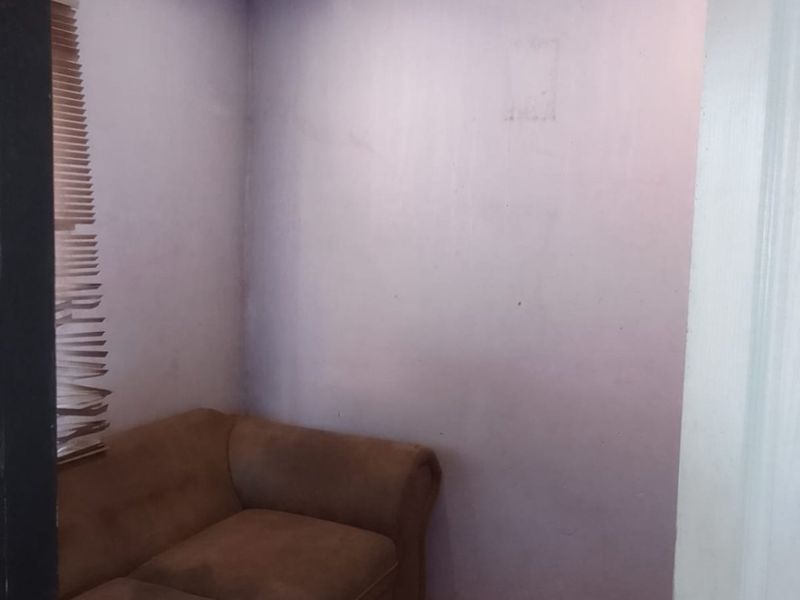 A small bedroom featuring tiled flooring, a beaded ceiling, and venetian blinds, currently requiring cosmetic updates to the wall finishes.