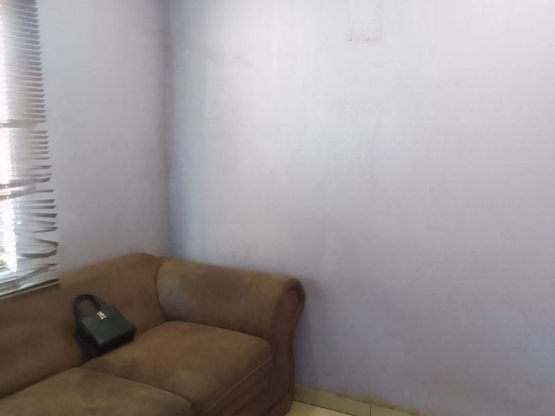 A small bedroom featuring tiled flooring, venetian blinds, and a paneled ceiling, currently requiring cosmetic updates to the wall finishes.