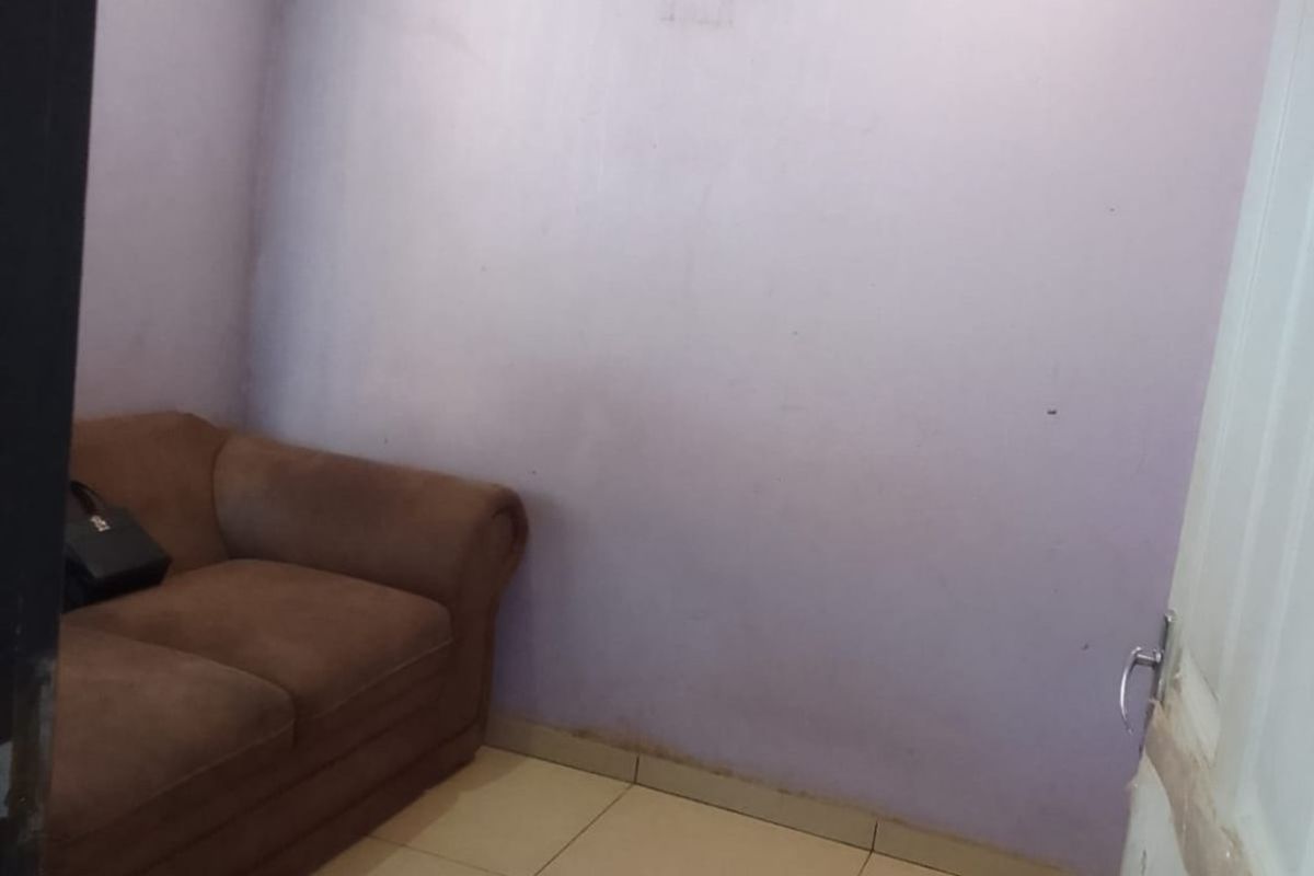 A small bedroom featuring tiled flooring and recessed ceiling lighting, currently requiring cosmetic updates to the wall finishes and door frame.