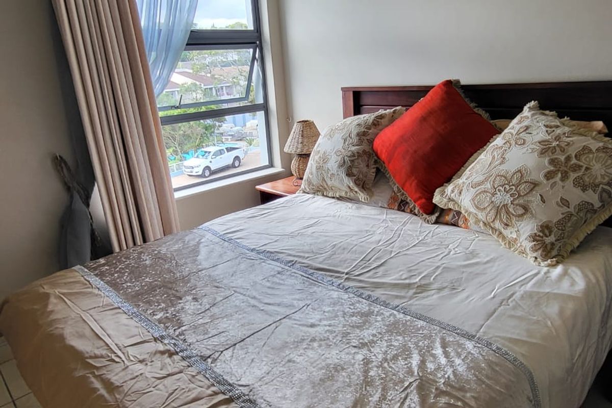 A bedroom featuring tiled flooring and an aluminium-framed window with views of the surrounding neighbourhood.