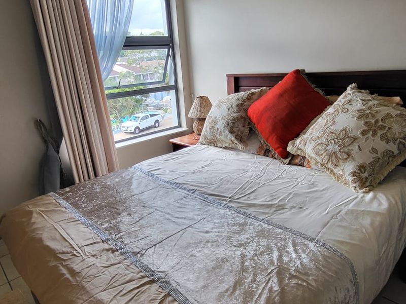 A bedroom featuring tiled flooring and an aluminium-framed window with views of the surrounding neighbourhood.