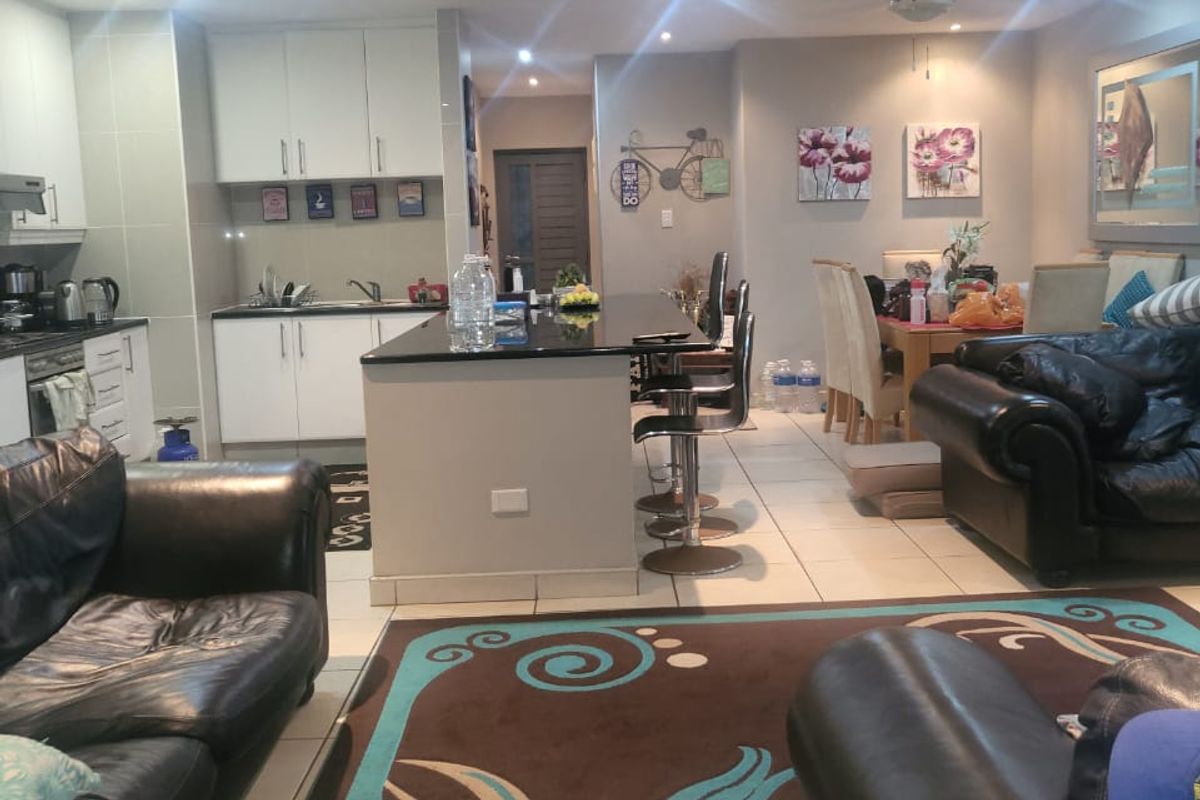 Open-plan living and kitchen area featuring a central island, tiled flooring, and recessed lighting, creating a functional and connected family space.