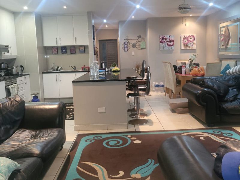 Open-plan living and kitchen area featuring a central island, tiled flooring, and recessed lighting, creating a functional and connected family space.
