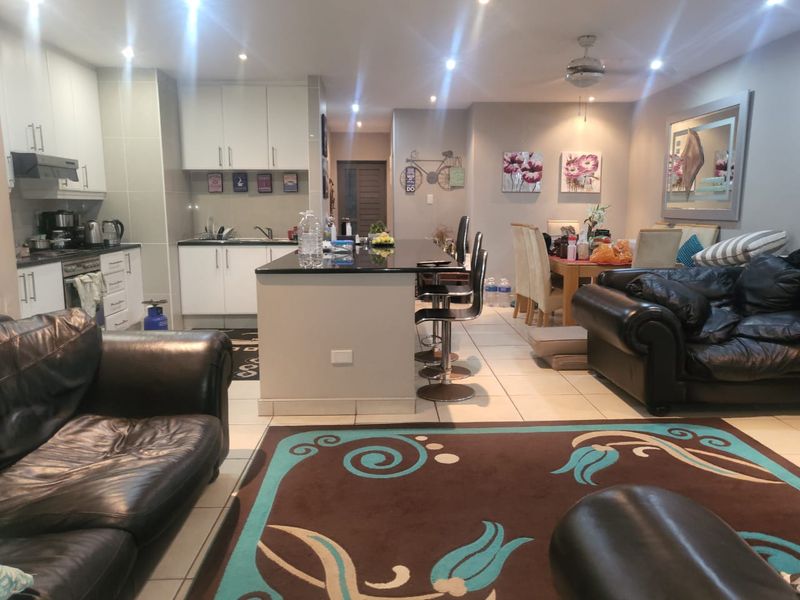 Spacious open-plan living area featuring a modern kitchen with a central island, granite countertops, and tiled flooring throughout.