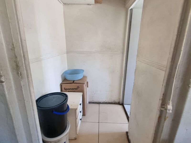 A small utility or storage area featuring tiled flooring and built-in shelving, currently showing signs of wear and requiring maintenance.