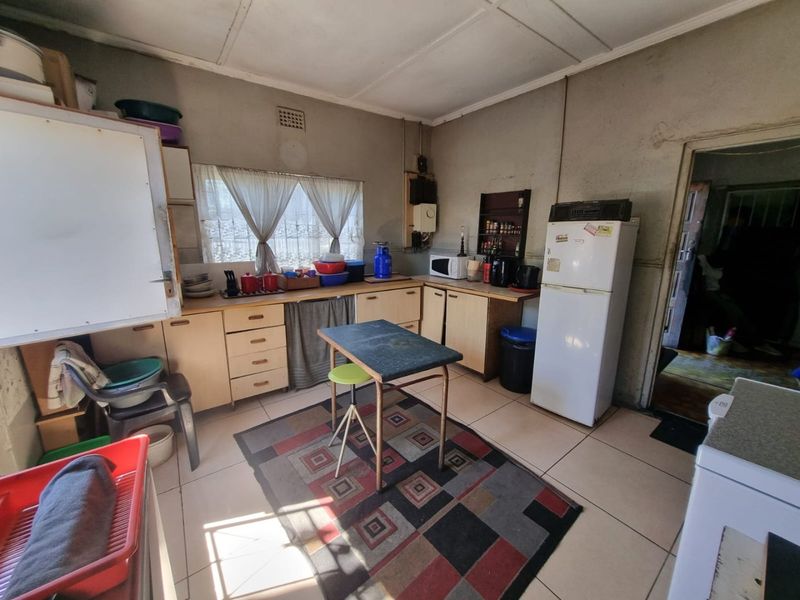 A functional kitchen featuring built-in cabinetry, laminate countertops, and tiled flooring, offering a dated aesthetic with potential for modernization.