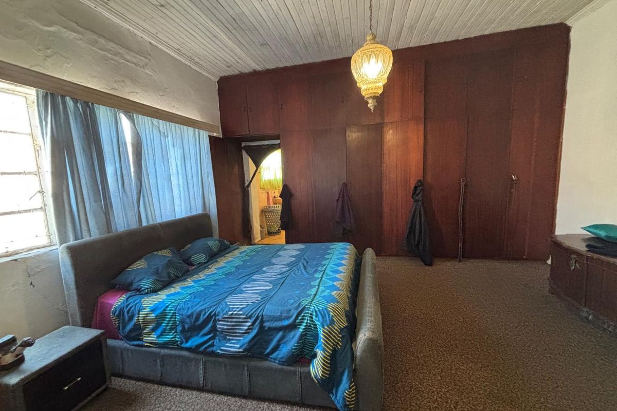 Spacious bedroom featuring extensive built-in wooden cabinetry, timber panelled ceilings, and carpeted flooring, offering significant potential for modernization and aesthetic updates.
