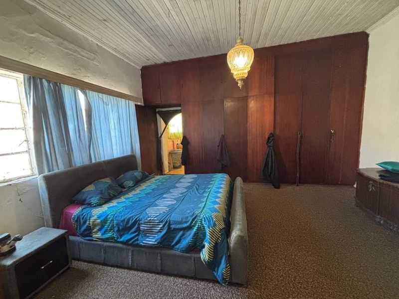 Spacious bedroom featuring extensive built-in wooden cabinetry, timber panelled ceilings, and carpeted flooring, offering significant potential for modernization and aesthetic updates.