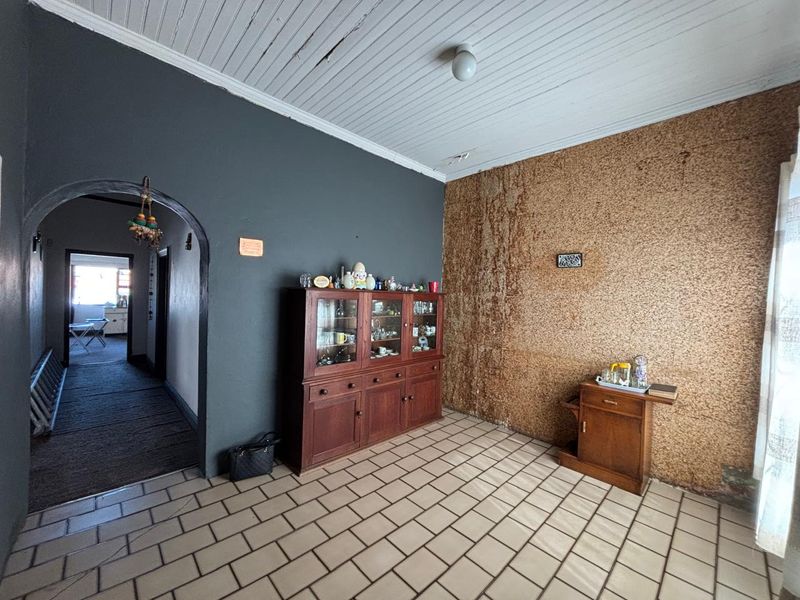 A living area featuring tiled flooring, an arched entryway, and a timber ceiling, currently requiring cosmetic updates to the wall and ceiling finishes.