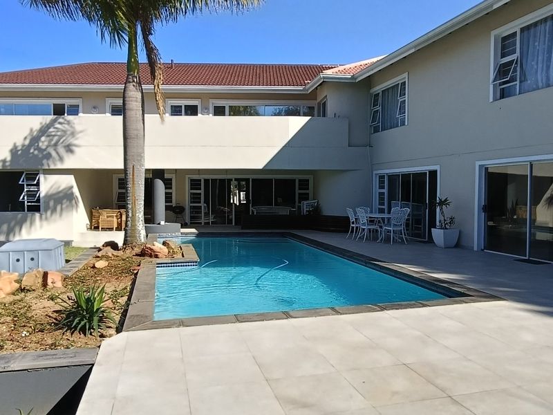 Spacious rear exterior featuring a swimming pool, tiled patio area, and large sliding doors providing seamless indoor-outdoor flow.