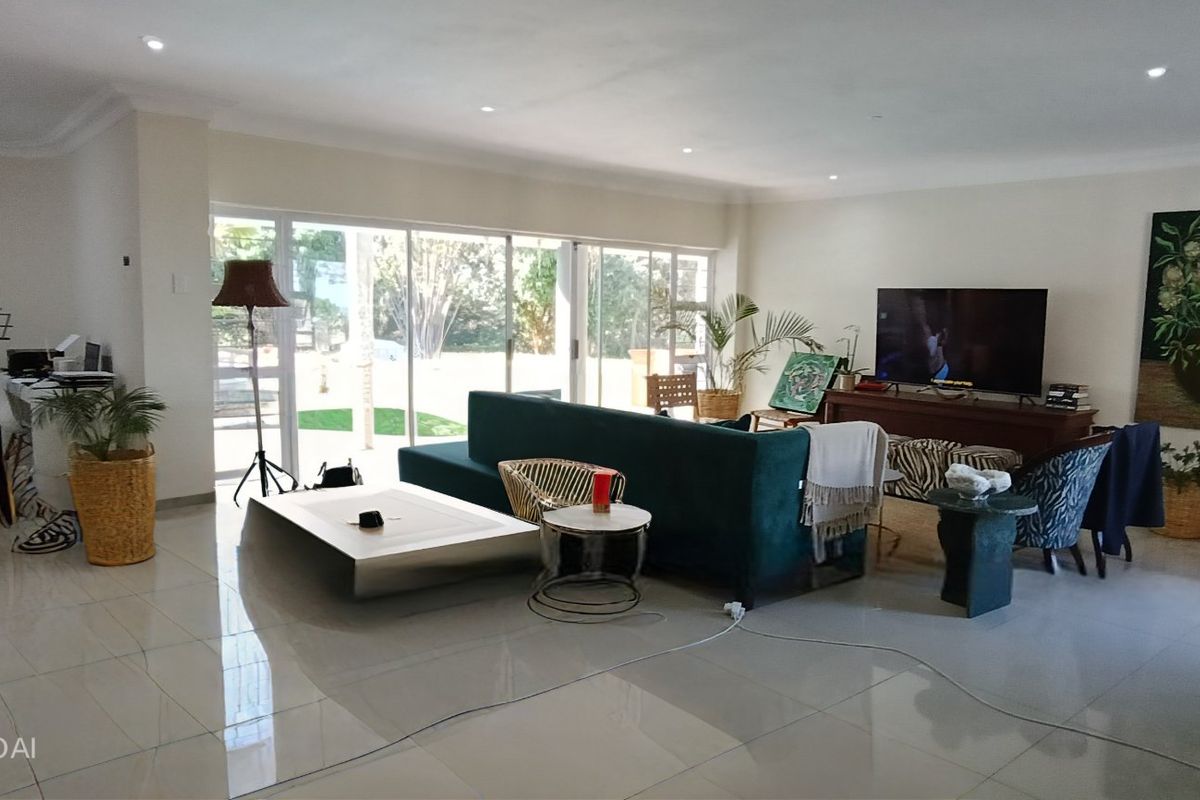 Spacious open-plan living area featuring large sliding glass doors, polished porcelain floor tiles, and recessed downlighting, offering a bright and modern atmosphere.