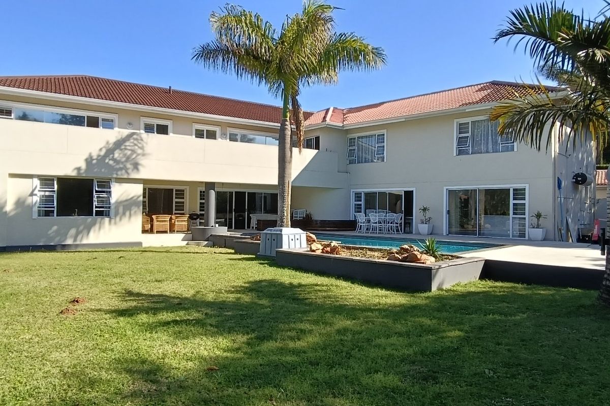Rear view of the townhouse featuring a spacious lawn, swimming pool, paved patio area, and large sliding doors leading into the home.