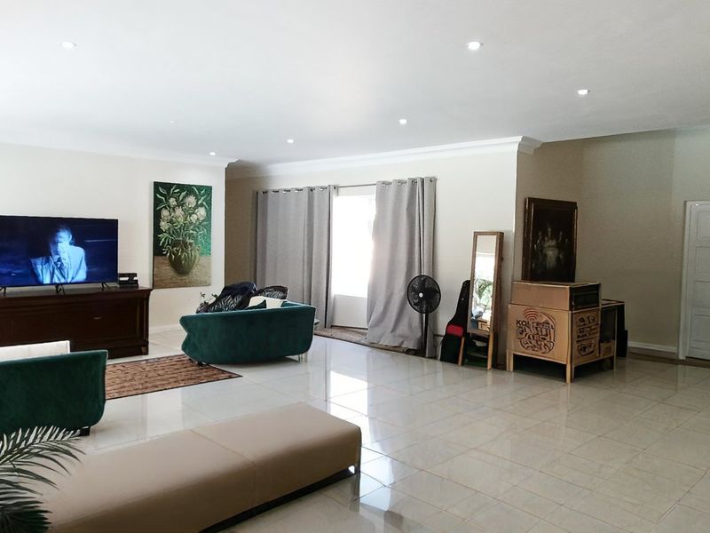 Spacious living room featuring neutral tiled flooring, recessed downlighting, and coved ceiling cornices, providing a bright and open atmosphere.