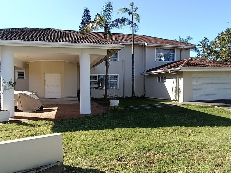 Front elevation of a townhouse featuring a covered entrance, paved driveway, and an integrated double garage with a tiled roof.