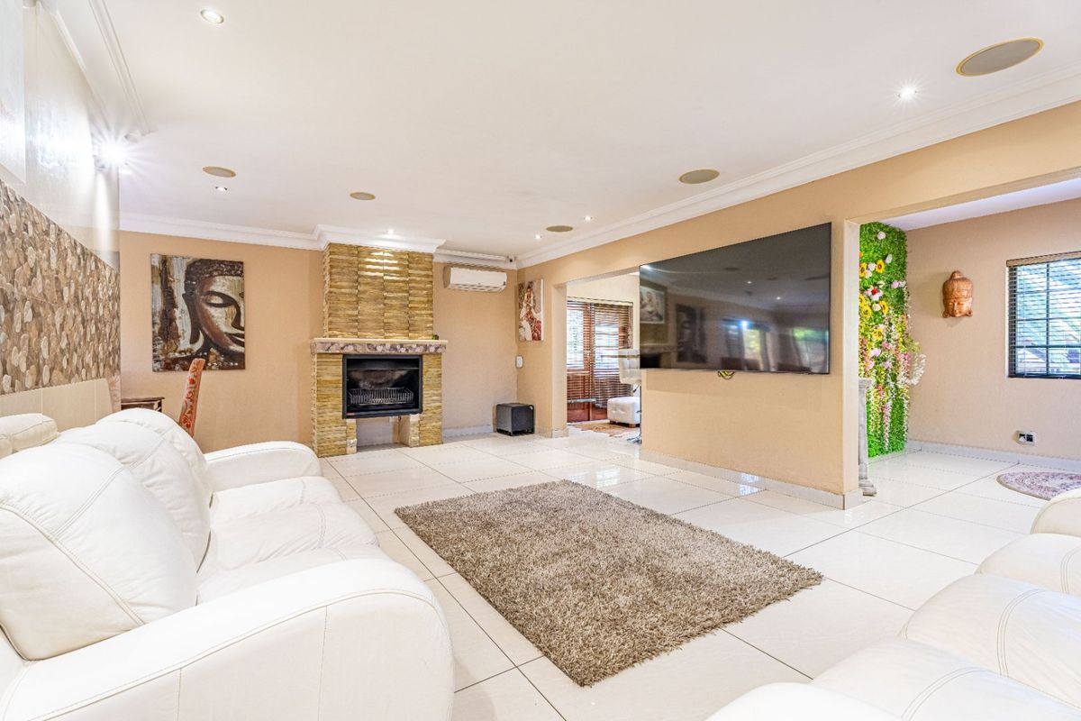 Spacious living room featuring tiled flooring, a stone-clad fireplace, recessed ceiling lighting, and integrated ceiling speakers.