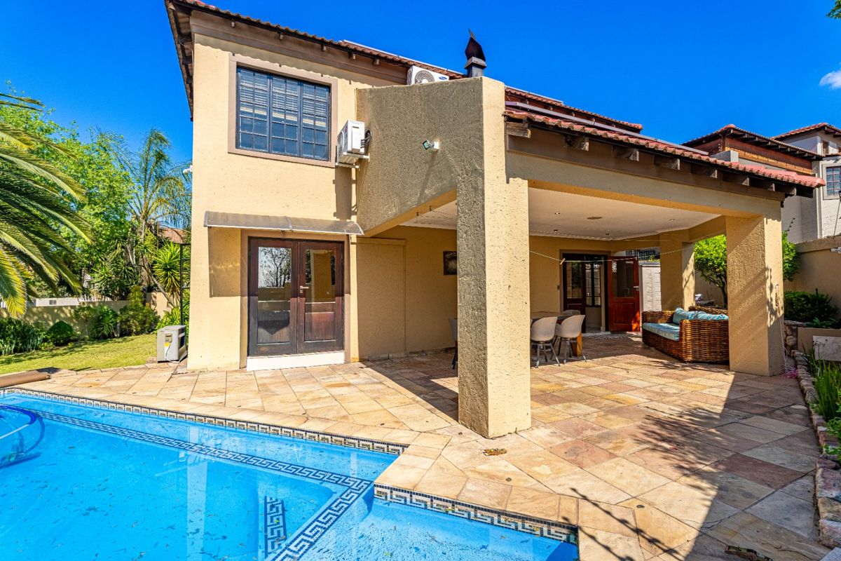 Rear exterior view featuring a covered patio area, tiled flooring, and a swimming pool set against the house facade.