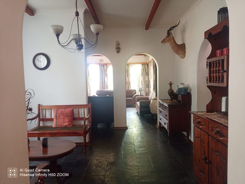 A living area featuring traditional arched doorways, exposed timber ceiling beams, and dark stone tile flooring, creating a classic, rustic atmosphere.