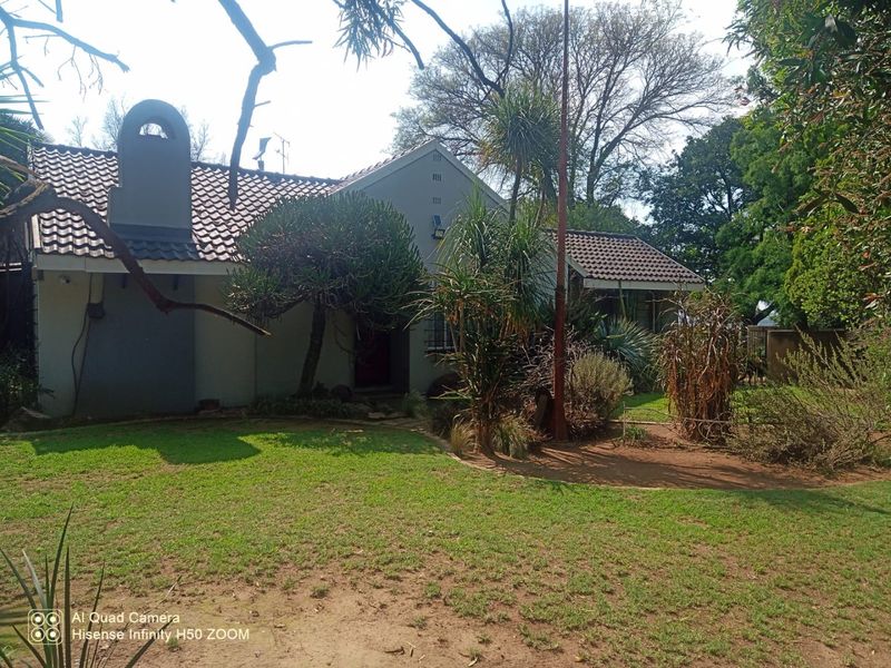 Front view of a residential house featuring a tiled roof, chimney, and established garden area.