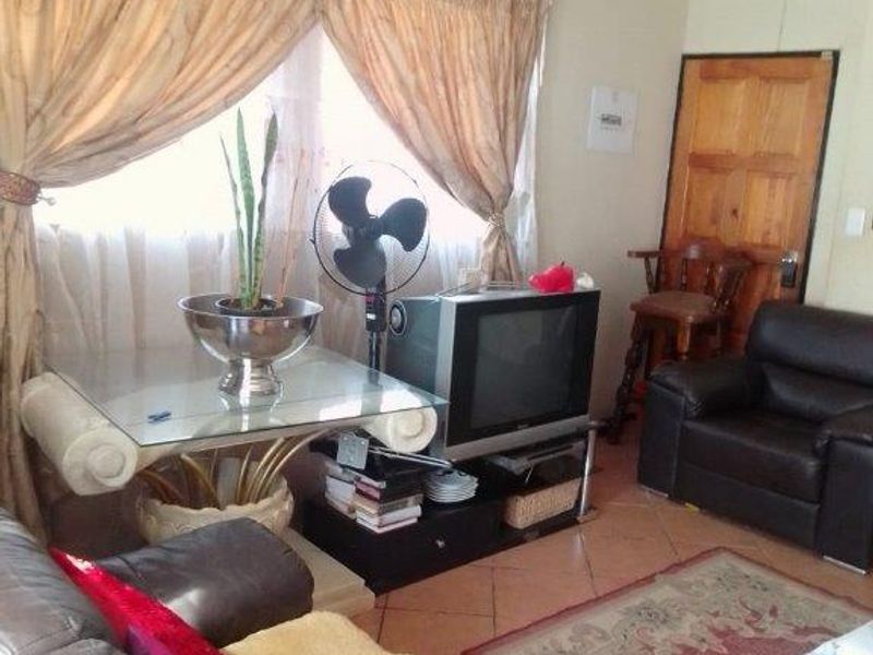 A living room area featuring tiled flooring and a wooden door, providing a functional space for relaxation.