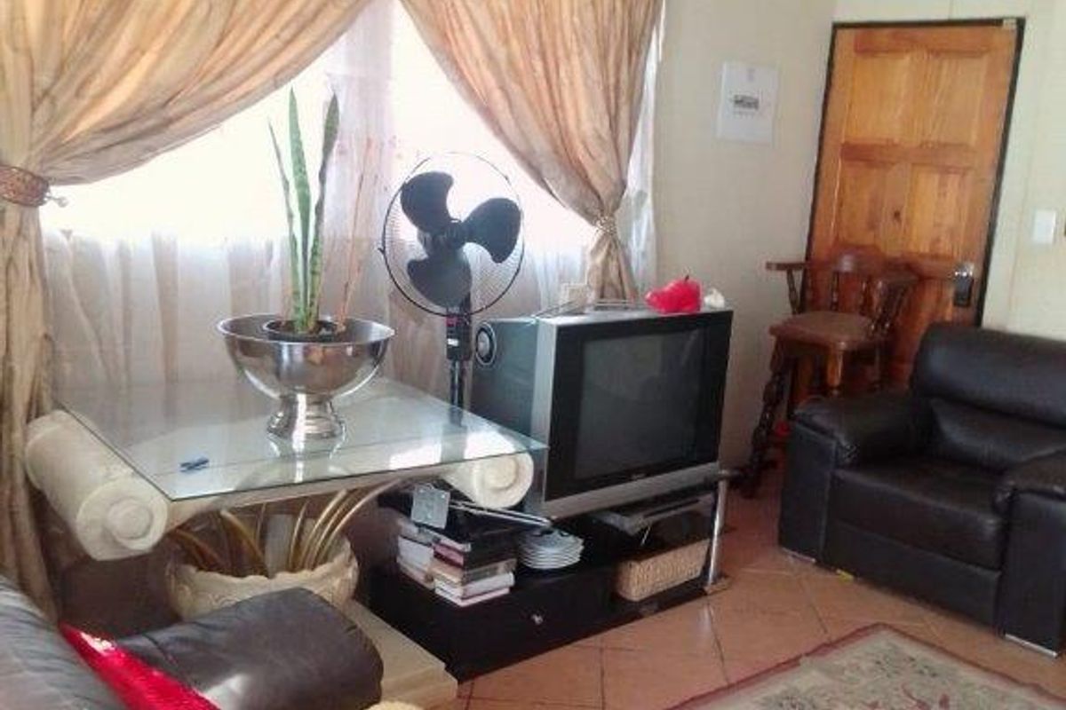 A living room area featuring tiled flooring and a wooden door, providing a functional space for relaxation.