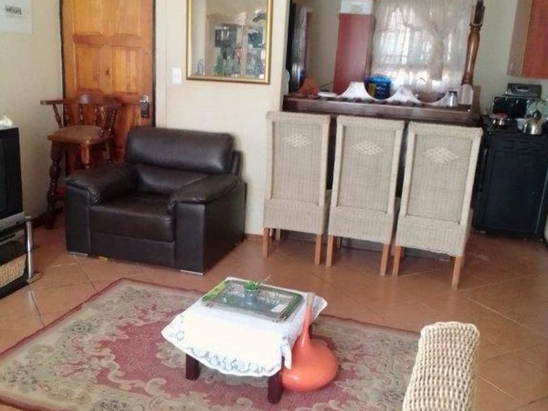 Open plan living area featuring tiled flooring, a breakfast bar, and a ceiling fan, with visible signs of wear on the ceiling and walls.