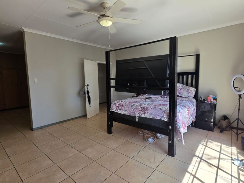Spacious bedroom featuring tiled flooring, a ceiling fan, and built-in cupboard storage.