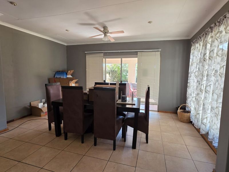 A dining room featuring tiled flooring, a ceiling fan, and a sliding glass door providing access to the outdoor area.