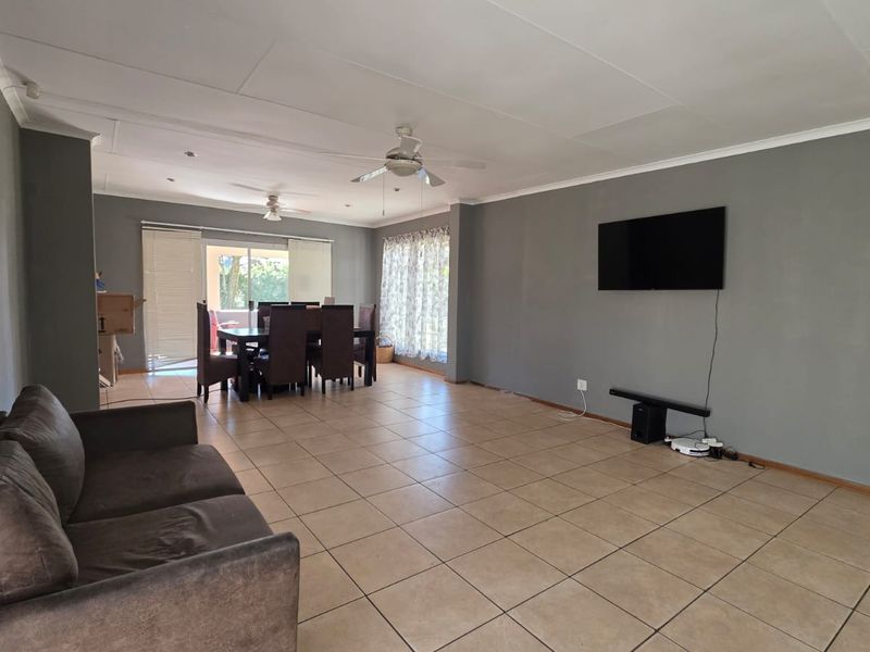 Spacious open-plan living and dining area featuring tiled flooring, ceiling fans, and direct access to the outdoor patio through sliding glass doors.