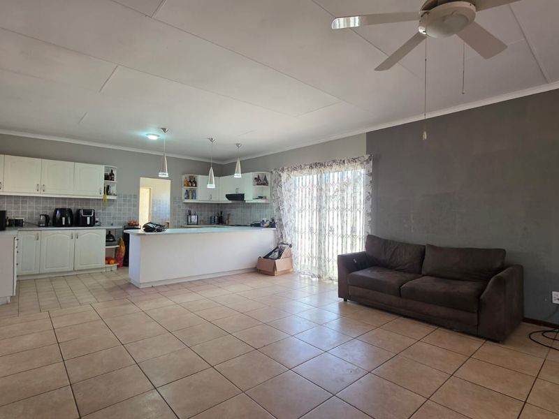 Open-plan living and kitchen area featuring tiled flooring, white cabinetry, a central island, and a sliding door leading to the exterior.