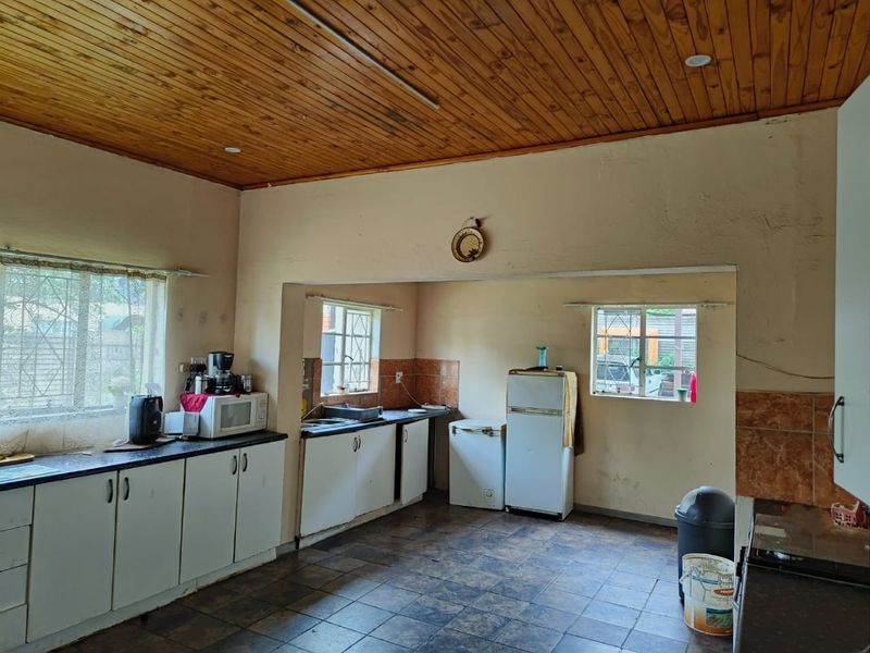 A functional kitchen featuring timber ceiling paneling, tiled flooring, and ample cabinetry, offering a dated aesthetic with potential for modern renovation.