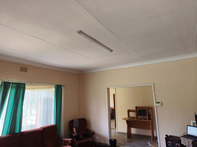 A living room area featuring neutral wall tones, a standard ceiling light fixture, and a doorway leading to an adjacent space.