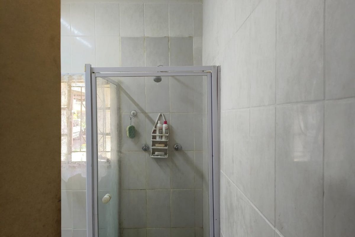 A functional bathroom featuring a shower enclosure with tiled walls and a window, presenting an opportunity for cosmetic updates.