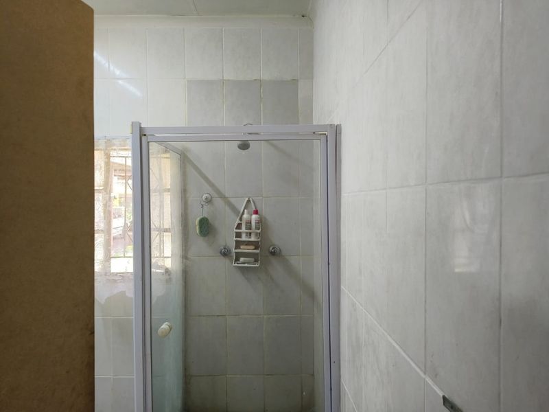 A functional bathroom featuring a shower enclosure with tiled walls and a window, presenting an opportunity for cosmetic updates.