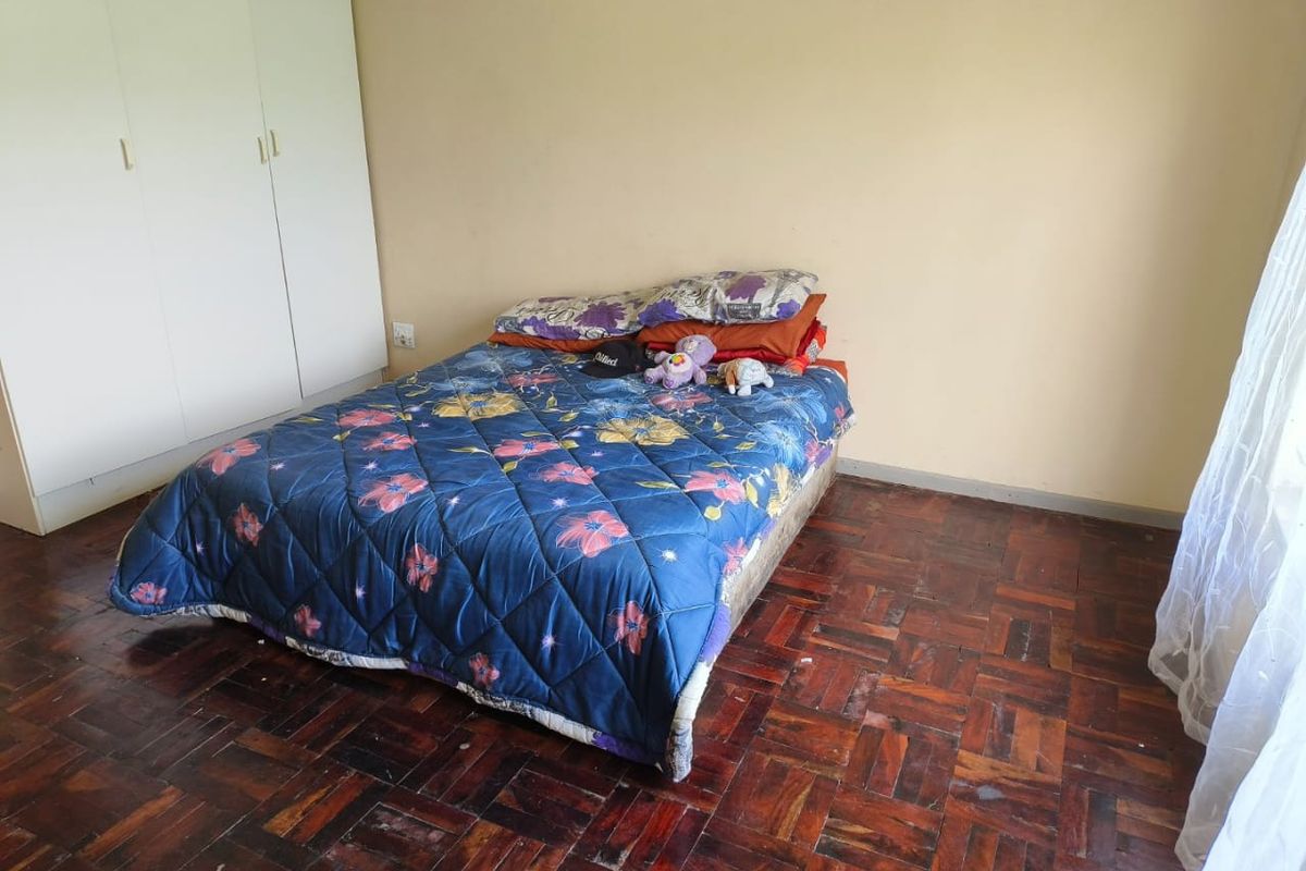 A bedroom featuring classic parquet flooring and a built-in wardrobe, offering a functional space ready for cosmetic updates.