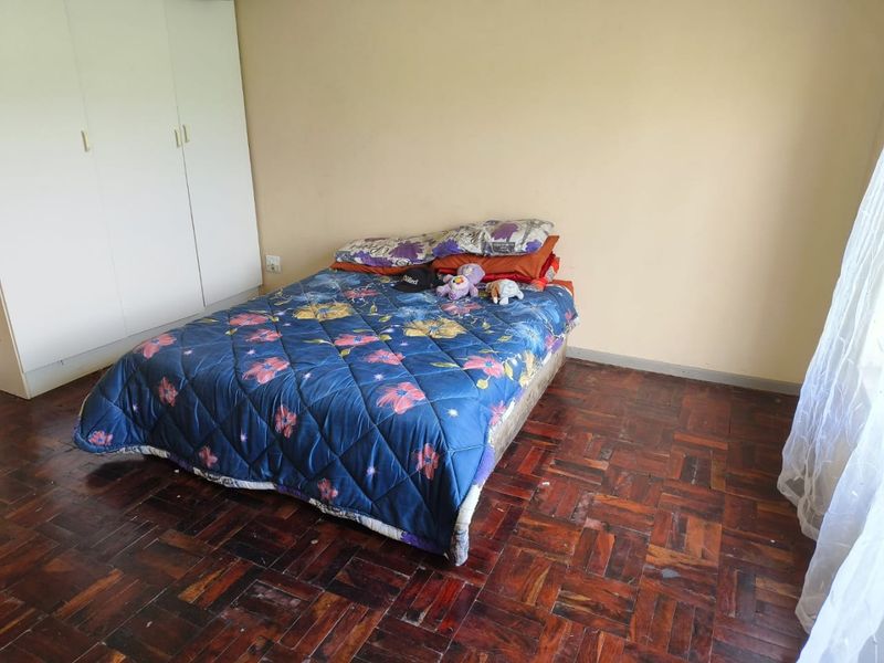A bedroom featuring classic parquet flooring and a built-in wardrobe, offering a functional space ready for cosmetic updates.