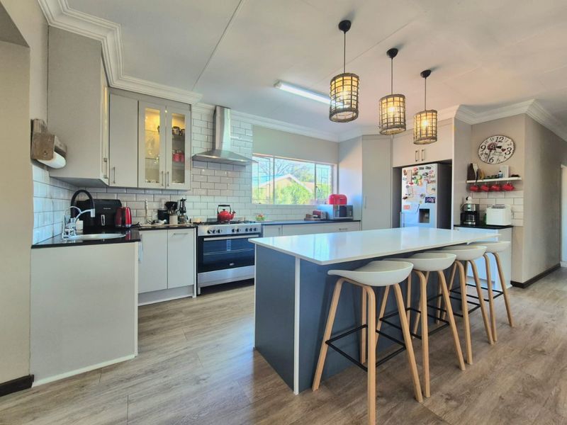 Modern kitchen featuring a central island with breakfast bar seating, subway tile backsplash, stainless steel gas stove, and ample built-in cabinetry.