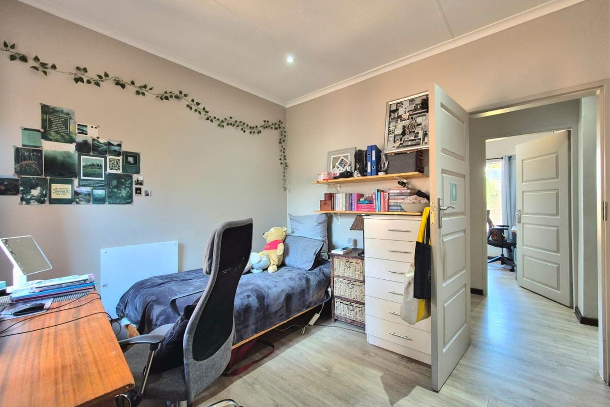 A functional bedroom featuring laminate flooring, neutral wall tones, and recessed ceiling lighting, providing a comfortable and well-lit living space.